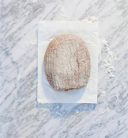placa de mármol - A loaf of bread on paper, on a marble surface, dusted with flour Foto de stock - Sin royalties Premium, Código: 659-06671595