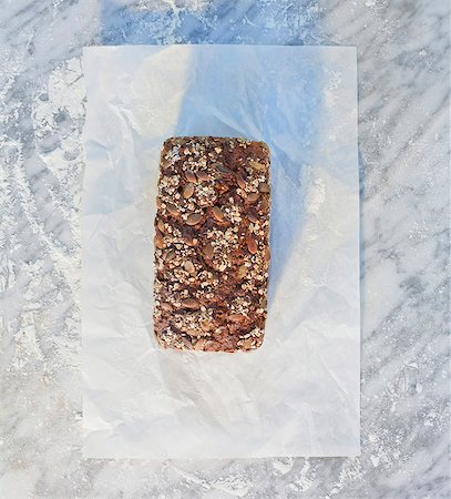 pumpkin seed - A tin-baked loaf topped with rolled oats, pumpkin seeds and sunflower seeds, on paper, on a marble slab dusted with flour Stock Photo - Premium Royalty-Free, Code: 659-06671592