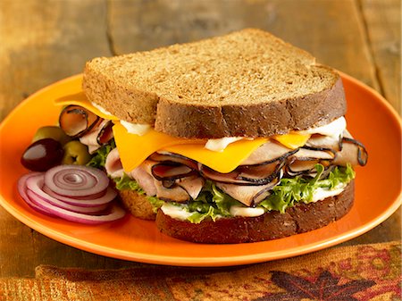 Turkey and Cheese Sandwich on Toasted Wheat Bread; Onion Slices and Olives; On a Plate Foto de stock - Sin royalties Premium, Código: 659-06901388