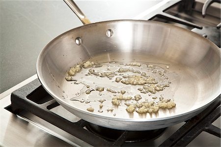 pfanne - Sauteing Minced Garlic in a Skillet with Olive Oil Foto de stock - Sin royalties Premium, Código: 659-06901399