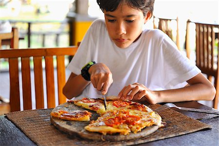 patio restaurant people - A boy slicing a pizza Stock Photo - Premium Royalty-Free, Code: 659-06901438