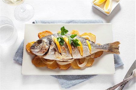 Grilled gilt-head bream with oranges on top of potato slices Photographie de stock - Premium Libres de Droits, Code: 659-06901792