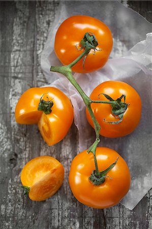 papel encerado - Tomatoes on the vine, one of which has a wedge cut out Foto de stock - Sin royalties Premium, Código: 659-06902044