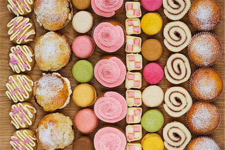 sweet dish - Rows of cupcakes, scones, macarons, Swiss rolls and pieces of mini-Battenburg cake Foto de stock - Sin royalties Premium, Código: 659-06902202