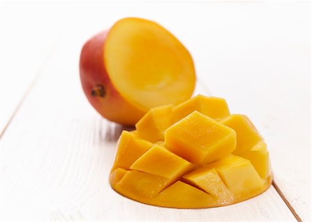 simsearch:695-05771725,k - A mango cut in half, with one half cut into chunks in a diamond pattern Stock Photo - Premium Royalty-Free, Code: 659-06902924