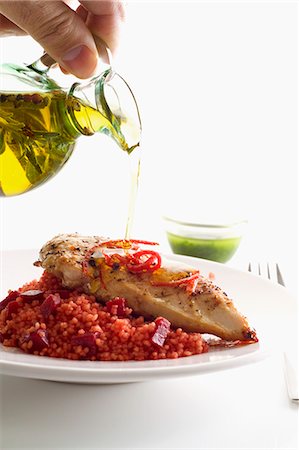 Olive oil being drizzled over a chicken breast on a bed of beetroot couscous Photographie de stock - Premium Libres de Droits, Code: 659-06902980