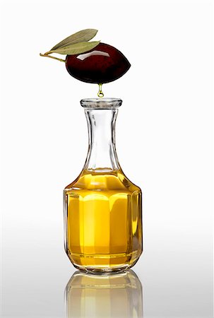 A black olive with an oil droplet over a carafe of olive oil Stock Photo - Premium Royalty-Free, Code: 659-06903078