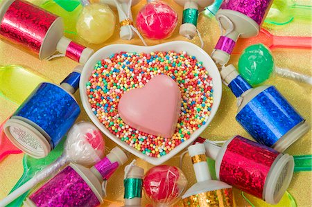 overview still life close up of heart dish with a pink chocolate heart shape and coloured party poppers and plastic ice cream spoons Stock Photo - Premium Royalty-Free, Code: 659-06903147