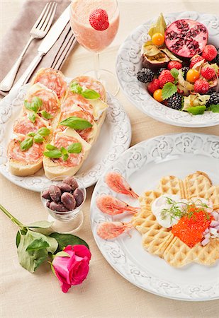 egg dish - A breakfast of a caviar-topped waffle, slices of bread topped with cheese and ham, fresh fruits and a strawberry and mango smoothie Stock Photo - Premium Royalty-Free, Code: 659-06903238