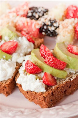 pão de milho - Rye bread with cottage cheese, strawberries and avocado; fruit and coconut skewers in the background Foto de stock - Royalty Free Premium, Número: 659-06903233