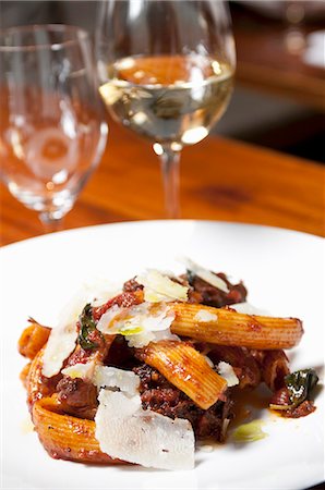 simsearch:659-06903372,k - Rigatoni with Short Ribs and Shaved Parmesan Cheese; On a White Plate; Glass of White Wine in Background Stock Photo - Premium Royalty-Free, Code: 659-06903353