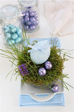 An egg decorated with a ribbon and chocolate eggs in an Easter nest made of moss and grass Photographie de stock - Premium Libres de Droits, Code: 659-06903497