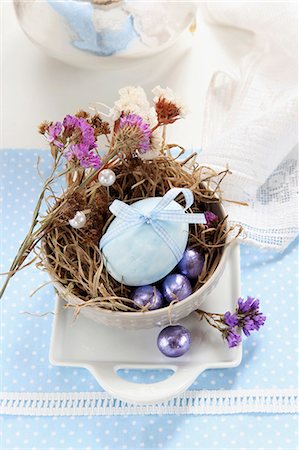 An egg decorated with a ribbon, dried flowers and chocolate eggs in an Easter nest made of moss and grass Photographie de stock - Premium Libres de Droits, Code: 659-06903498