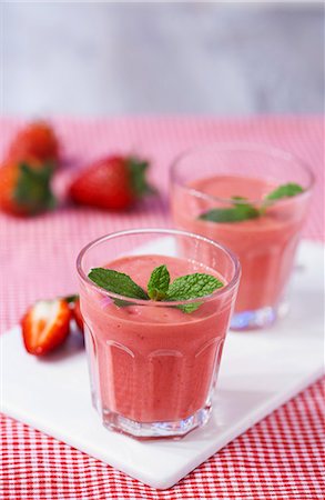 simsearch:659-06373374,k - Strawberry smoothies topped with mint leaves on a chopping board on a red gingham tablecloth Foto de stock - Sin royalties Premium, Código: 659-06903550