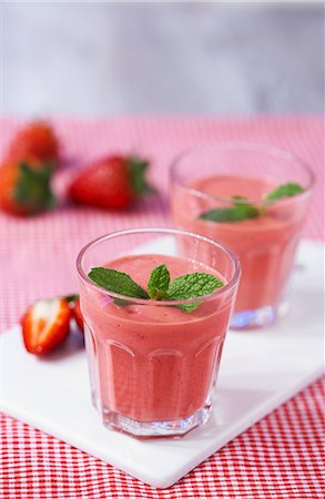 simsearch:659-07958640,k - Strawberry smoothies topped with mint leaves on a chopping board on a red gingham tablecloth Foto de stock - Sin royalties Premium, Código: 659-06903550