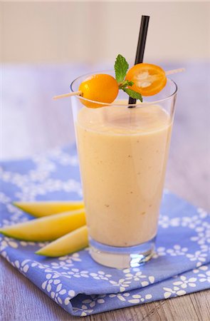 An exotic smoothie with mango and kumquats on a blue napkin on a wooden tabletop Stock Photo - Premium Royalty-Free, Code: 659-06903553