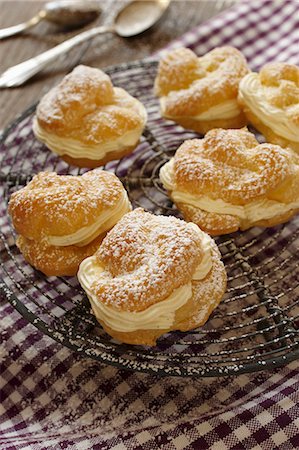 puff - Profiteroles dusted with icing sugar, on a cooling rack Stock Photo - Premium Royalty-Free, Code: 659-06903624