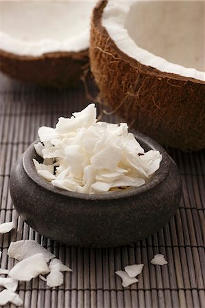 A coconut, broken open, and coconut shavings, on a bamboo mat (close-up) Foto de stock - Sin royalties Premium, Código: 659-06903884