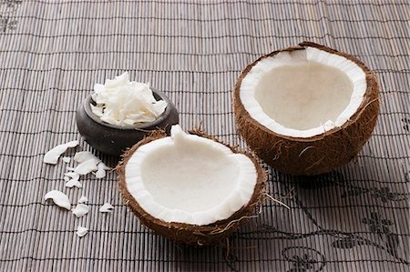 A broken-open coconut and coconut shavings on a bamboo mat Stock Photo - Premium Royalty-Free, Code: 659-06903883