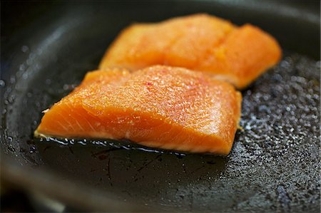 sauteeing - Salmon trout being fried in a pan Foto de stock - Sin royalties Premium, Código: 659-06903901