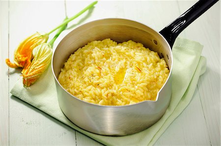 Saffron risotto in a pan, zucchini blossoms in the background Photographie de stock - Premium Libres de Droits, Code: 659-06903966