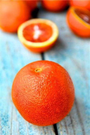 simsearch:659-09124296,k - A blood orange with blood orange halves in the background Stock Photo - Premium Royalty-Free, Code: 659-06903978