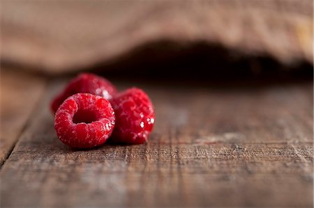 fokus auf hintergrund - Three frozen raspberries on a rustic surface Stockbilder - Premium RF Lizenzfrei, Bildnummer: 659-06903982