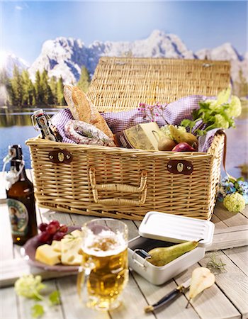 A table with a light meal and a picnic basket against a mountain view Fotografie stock - Premium Royalty-Free, Codice: 659-06903999