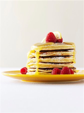 A Stack of Pancakes with Powdered Sugar, Honey and Raspberries Stock Photo - Premium Royalty-Free, Code: 659-07026829