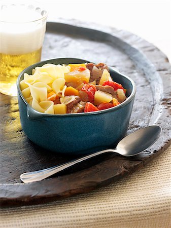 Noodles and Beef Goulash in a Bowl; Spoon and a Glass of Beer Foto de stock - Sin royalties Premium, Código: 659-07026833