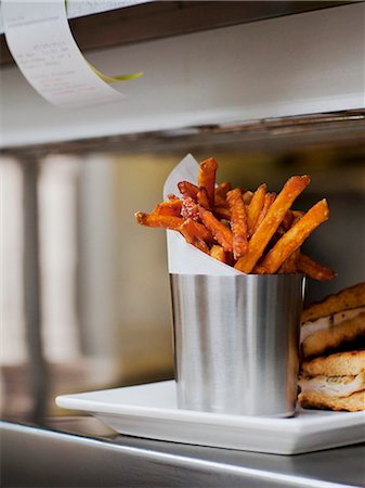 fries - Seasoned Fries with Wax Paper in a Steel Cup on a Restaurant "Order-Up" Counter Stockbilder - Premium RF Lizenzfrei, Bildnummer: 659-07026846