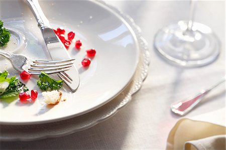 Dinner Remains on a White Plate; Pomegranate Seeds, Kale, Fork and Knife Stock Photo - Premium Royalty-Free, Code: 659-07026861