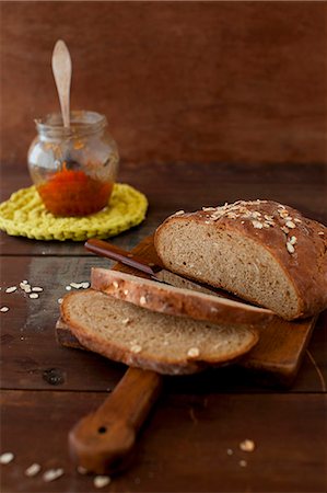 simsearch:659-07598766,k - Partially Sliced Loaf of Oat Bread on a Cutting Board; Jar of Jam Photographie de stock - Premium Libres de Droits, Code: 659-07027077