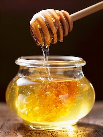 Honey dripping from a honey spoon into a jar Foto de stock - Sin royalties Premium, Código: 659-07027180