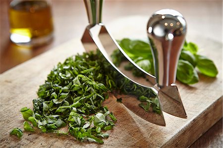 Basil being chopped with a curved chopping knife on a wooden board Stock Photo - Premium Royalty-Free, Code: 659-07027332