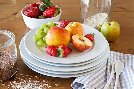 A still life featuring a stack of plates, fresh strawberries, apples and cereal grains Foto de stock - Sin royalties Premium, Código: 659-07027664