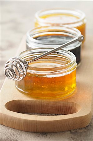 Three jars of honey on a chopping board Stock Photo - Premium Royalty-Free, Code: 659-07027882