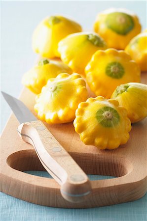 Several yellow patty pan squash on a chopping board with a knife Stock Photo - Premium Royalty-Free, Code: 659-07027916