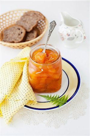 An Open Jar of Melon Jam with a Spoon; Basket of Bread Foto de stock - Royalty Free Premium, Número: 659-07028011