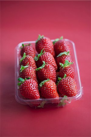 simsearch:659-06903612,k - Fresh strawberries in a plastic punnet on a Bordeaux-red surface Photographie de stock - Premium Libres de Droits, Code: 659-07028158