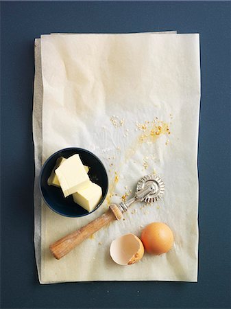 Butter, a pastry wheel and egg shells on grease-proof paper Foto de stock - Sin royalties Premium, Código: 659-07028168