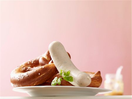 Pretzels and a white sausage; in the background a jar of mustard Stockbilder - Premium RF Lizenzfrei, Bildnummer: 659-07028752