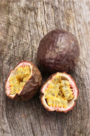 fruit flesh - Red passion fruit, whole and halved, on a wooden surface Stock Photo - Premium Royalty-Free, Code: 659-07028832