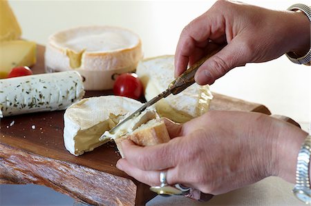 Slices of baguette being spread with Camembert, assorted types of cheese on a chopping board Foto de stock - Sin royalties Premium, Código: 659-07028863