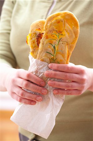 A woman holding snack-size oblong pizzas topped with potato and rosemary Stock Photo - Premium Royalty-Free, Code: 659-07068500