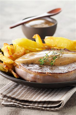 Pork fillet wrapped in bacon with roast potatoes and gravy Foto de stock - Sin royalties Premium, Código: 659-07068659