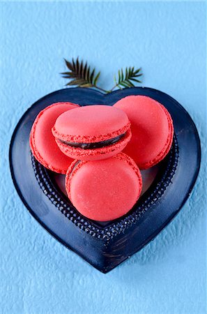 sweet food - Raspberry macaroons with chocolate filling in a heart-shaped dish on a blue surface Stock Photo - Premium Royalty-Free, Code: 659-07068864