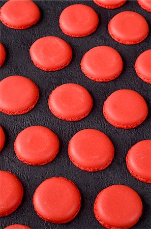 pastel francês - Freshly baked red macaroon halves on a slate surface Foto de stock - Royalty Free Premium, Número: 659-07068863