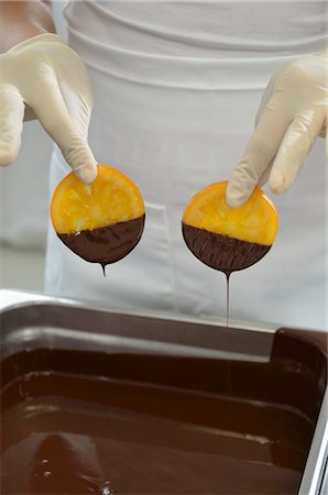 A chocolatier dipping candied orange slices into melted chocolate Photographie de stock - Premium Libres de Droits, Code: 659-07068889