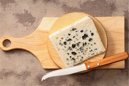 A wedge of blue cheese on a wooden board with a knife Stock Photo - Premium Royalty-Free, Code: 659-07068971